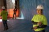 A female construction worker stands near two male workers during a ceremony to mark the completion of a new building.