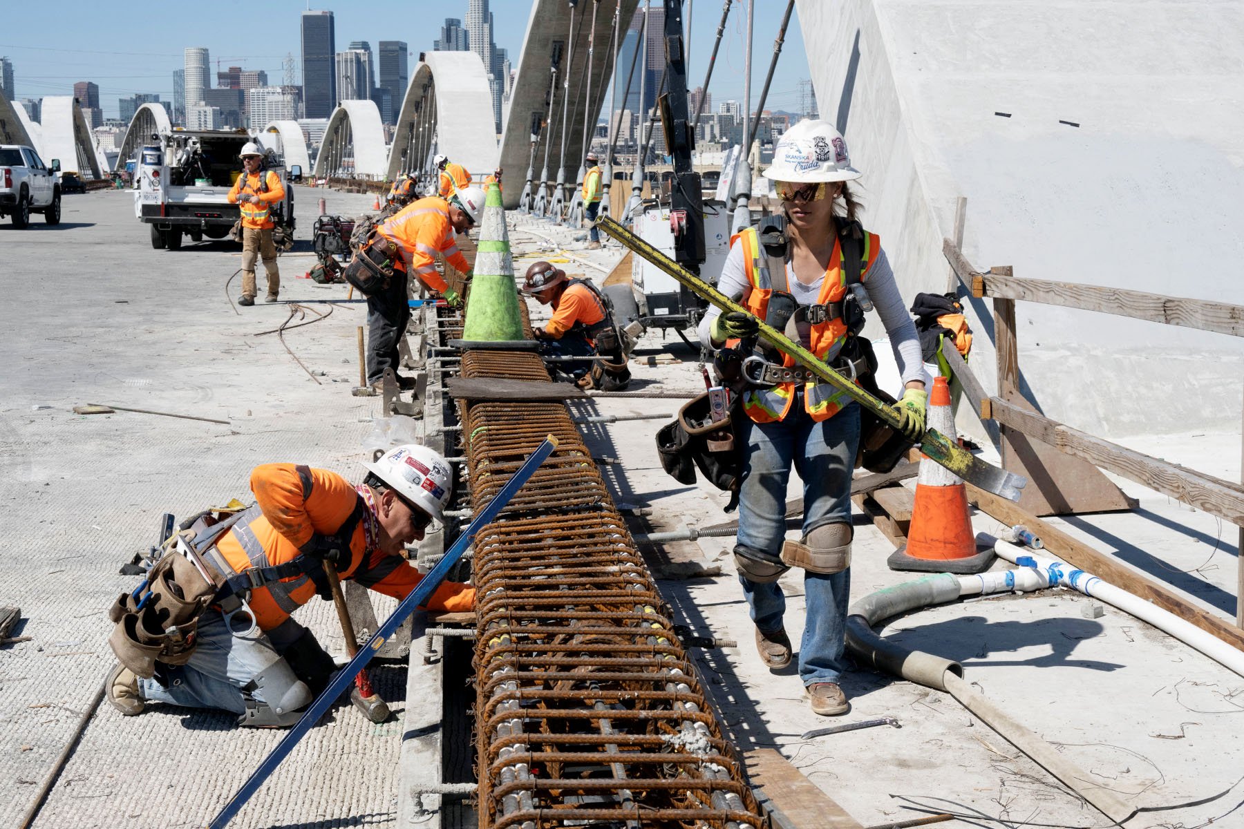 Construction workers, including a female worker, complete a rebar on the deck of a new Los Angeles bridge.