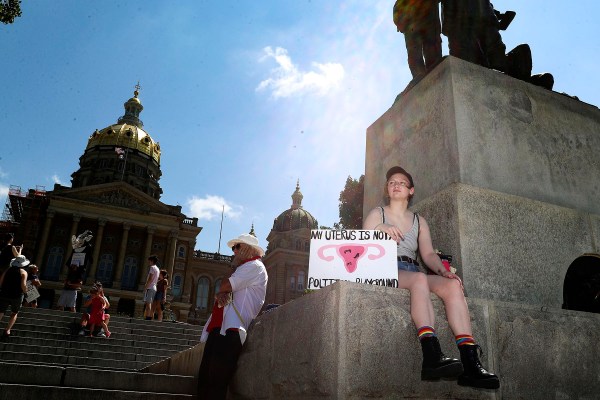 An abortion rights protester waits for the start of a rally for reproductive freedom on at the Iowa State Capitol Building. They hold a sign that reads 