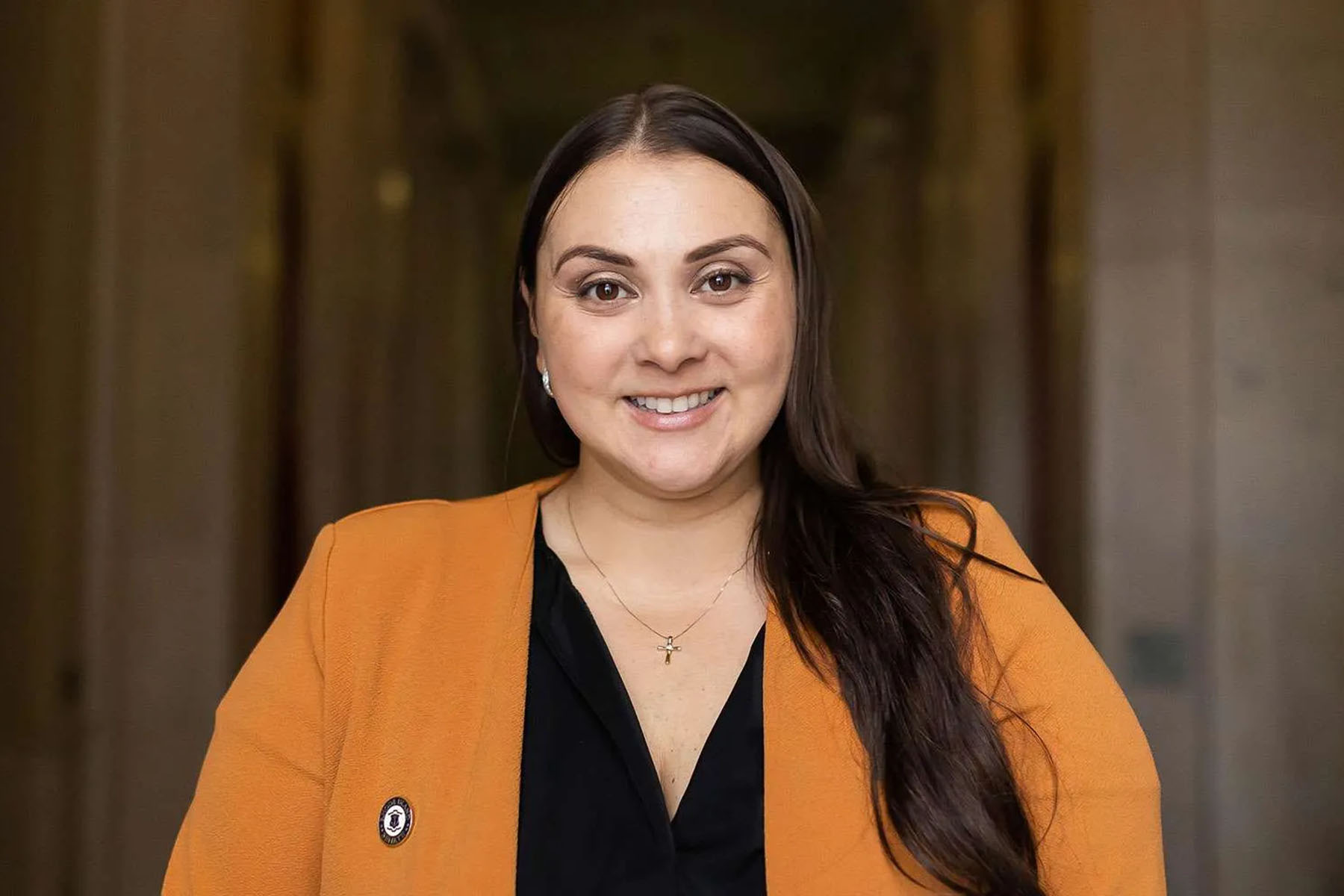 Smiling portrait of Sandra Cano wearing an orange blazer.