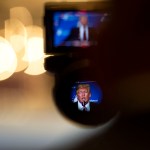 President Trump is seen giving a speech through a camera eyepiece.