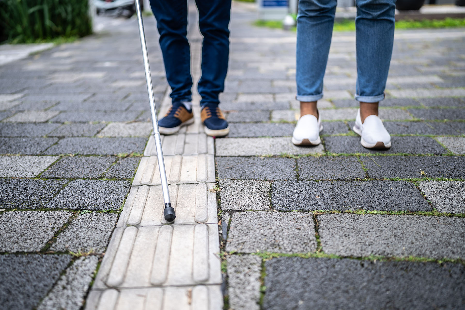 image of visually impaired people holding a cane walking down the street.