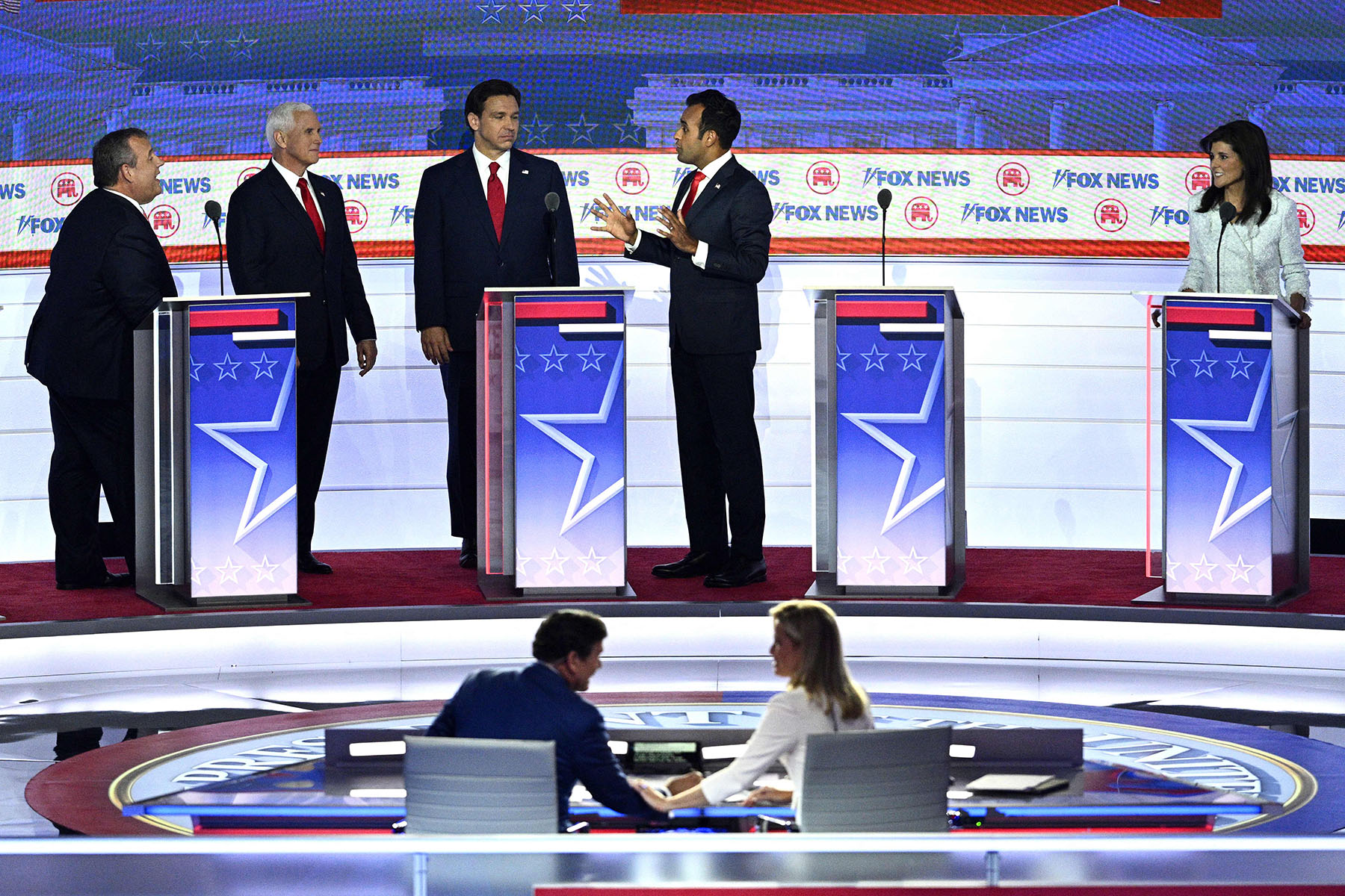 Nikki Haley looks on as Chris Christie, Mike Pence, Ron DeSantis and Vivek Ramaswamy speak on stage during a break in the first Republican Presidential primary debate.