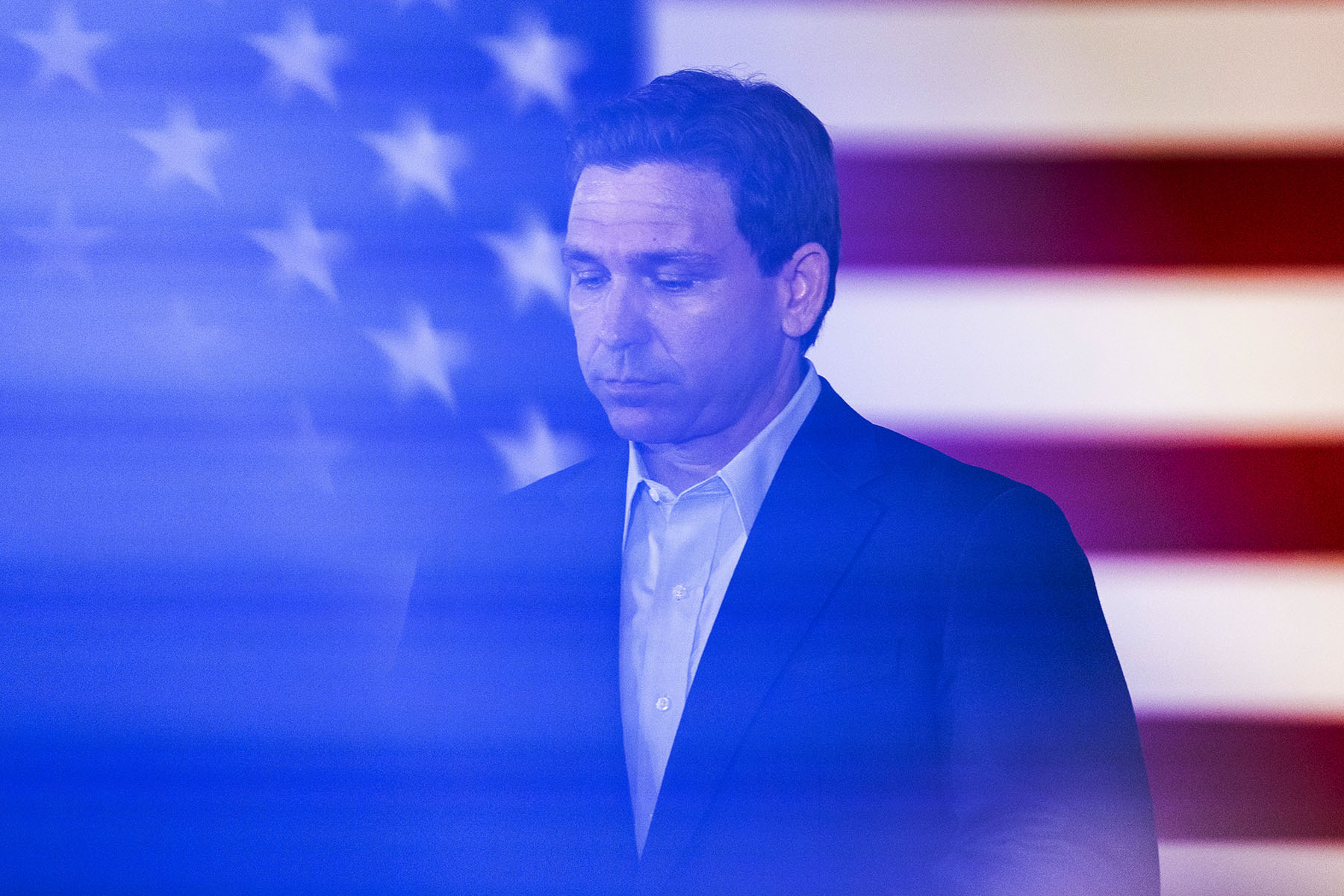 Governor Ron DeSantis speaks in front of a large american flag during a town hall event.