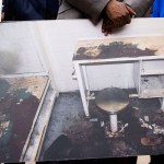 Attorney Michael Harper holds a photo of Lashawn Thompson's cell at the Fulton County Jail at a news conference. The cell is filthy, and filled with dirt and garbage. The furniture is rusted over and in terrible condition.
