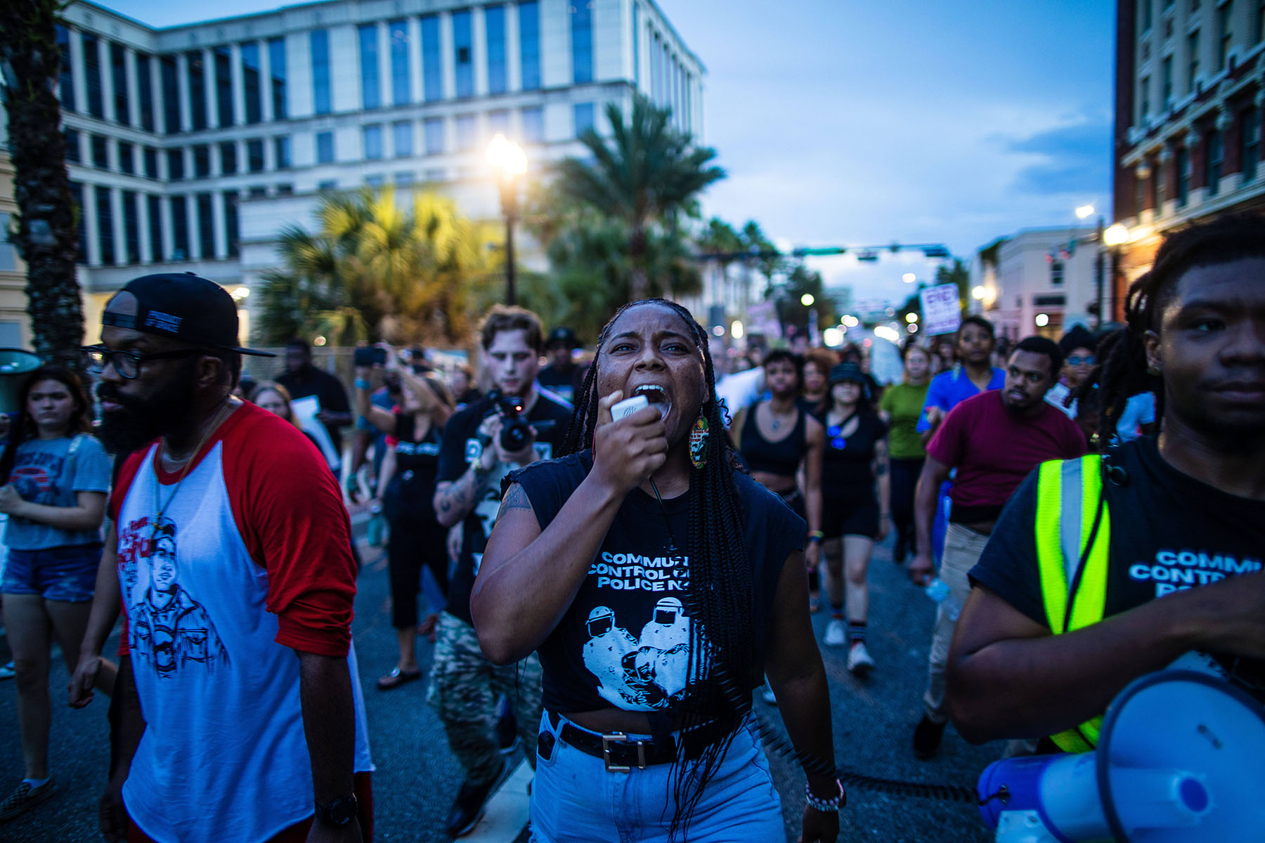 A woman chants slogan into a megaphone as people march to honor the victims of a deadly shooting in Jacksonville, Florida.