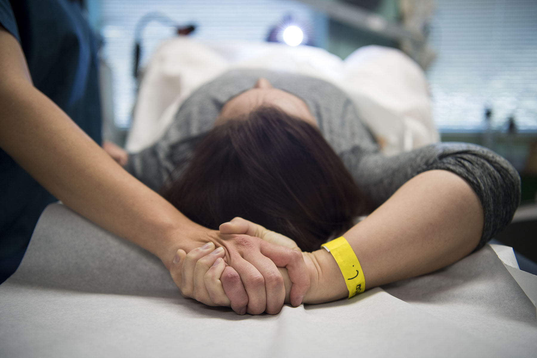 An abortion doula holds hands with a patient during a procedure at an abortion clinic.