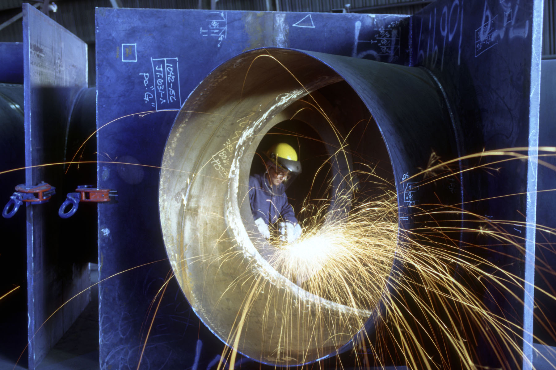 A female welder works on a pipe.