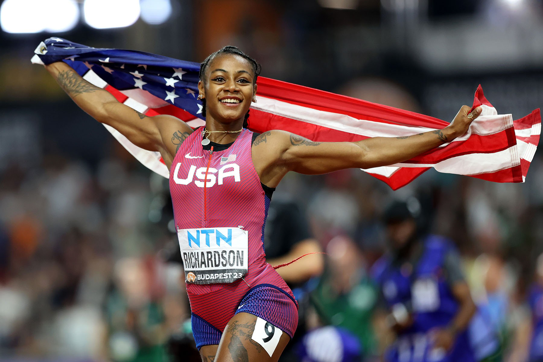 Sha'Carri Richardson celebrates with an American flag after winning a race.