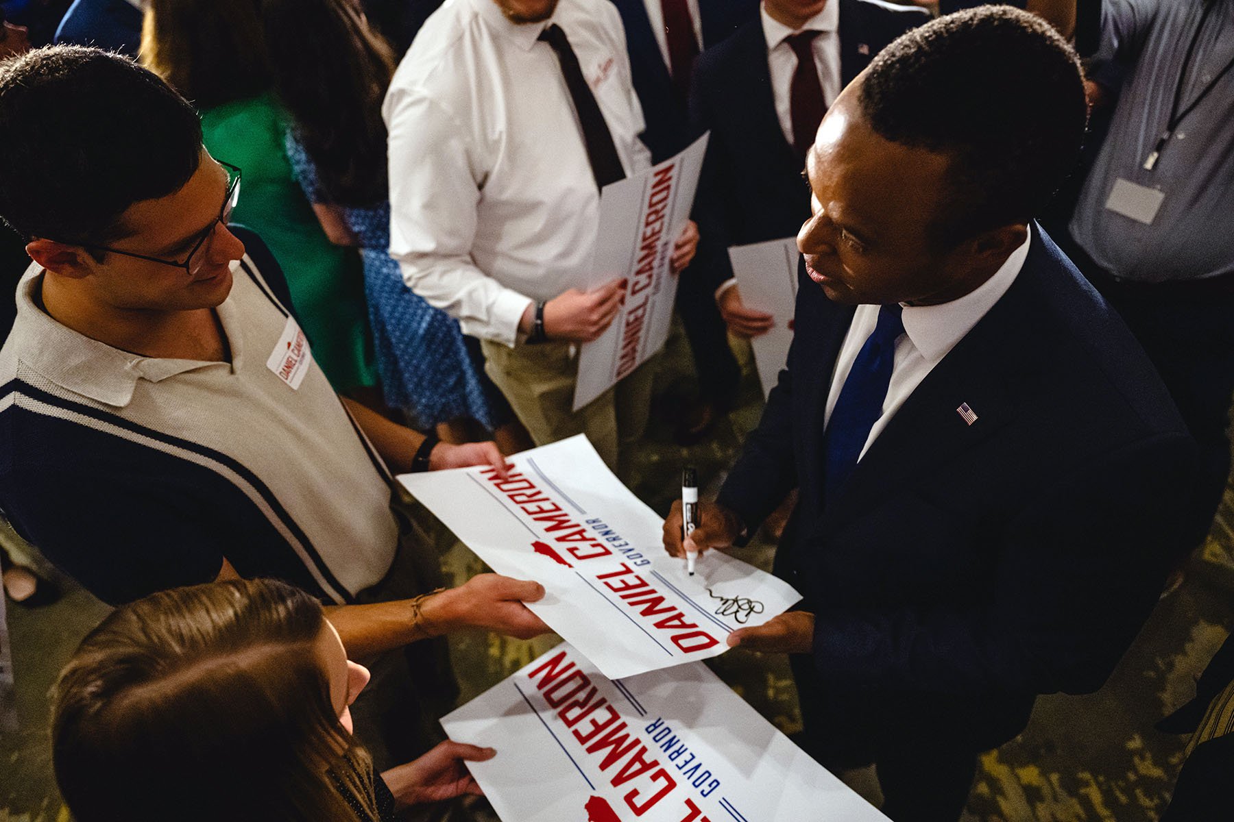 Kentucky Attorney General Daniel Cameron signs a campaign sign for a supporter.