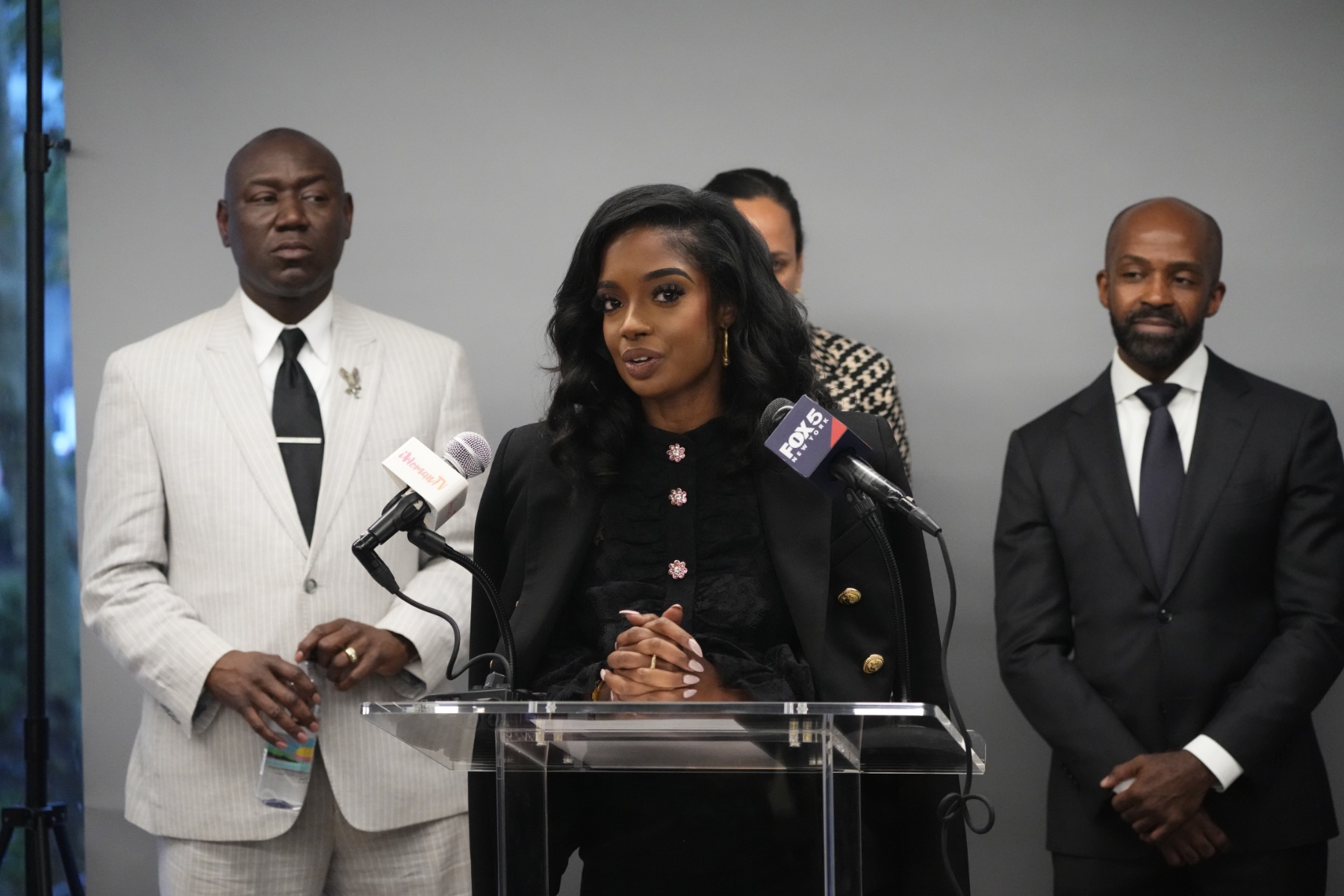 Arian Simone speaks at a news conference, with attorneys Ben Crump and Alphonso David.