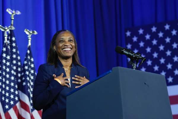 EMILY's List President Laphonza Butler speaks in front of a blue backdrop and American flags