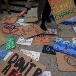 An activist picks up a placard during a Global Climate Strike. Posters are all over the floor and read 