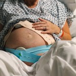 An unrecognisable mature pregnant woman lies on a hospital delivery bed as her baby's heart rate is being monitored.