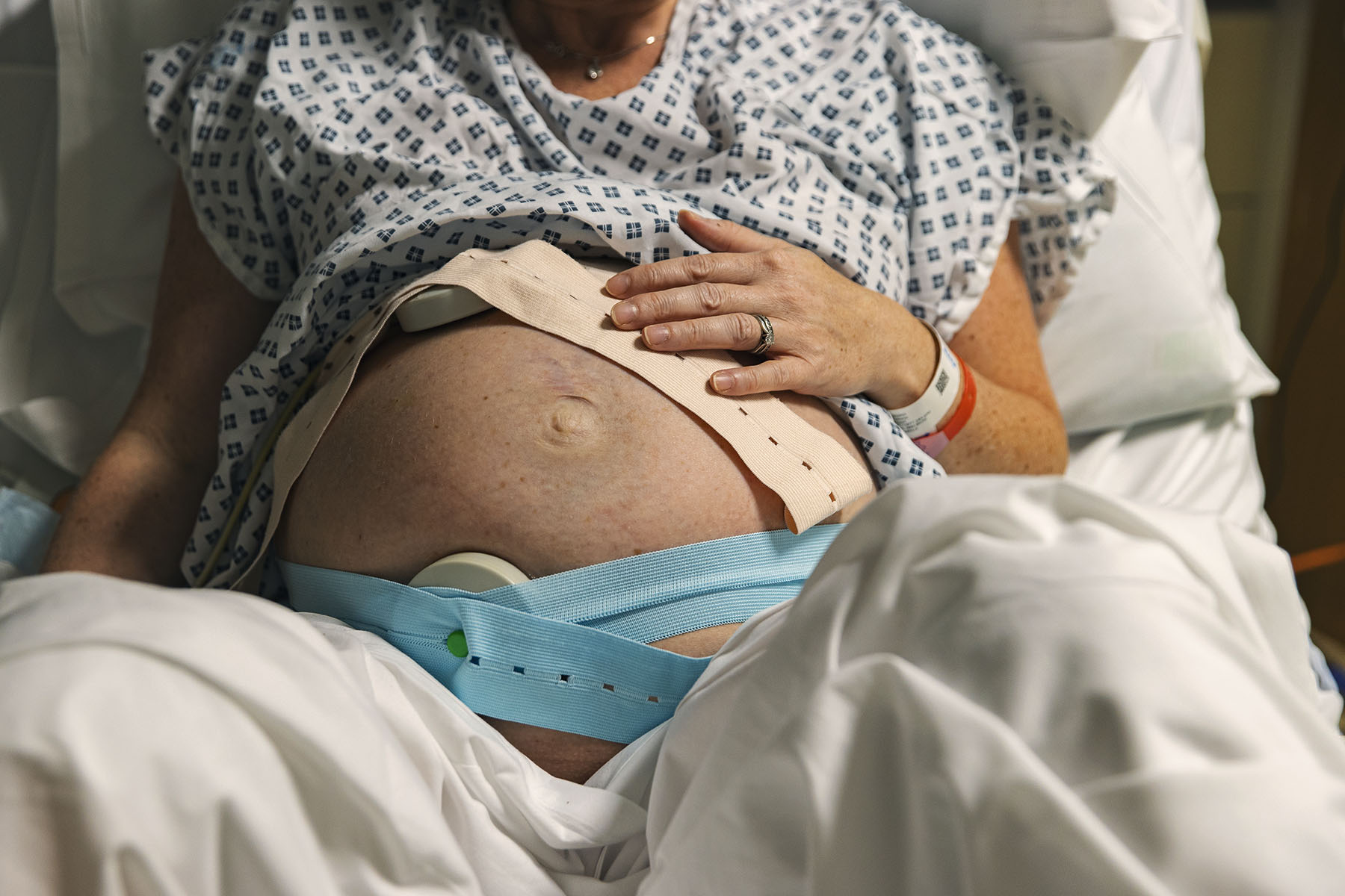 An unrecognisable mature pregnant woman lies on a hospital delivery bed as her baby's heart rate is being monitored.