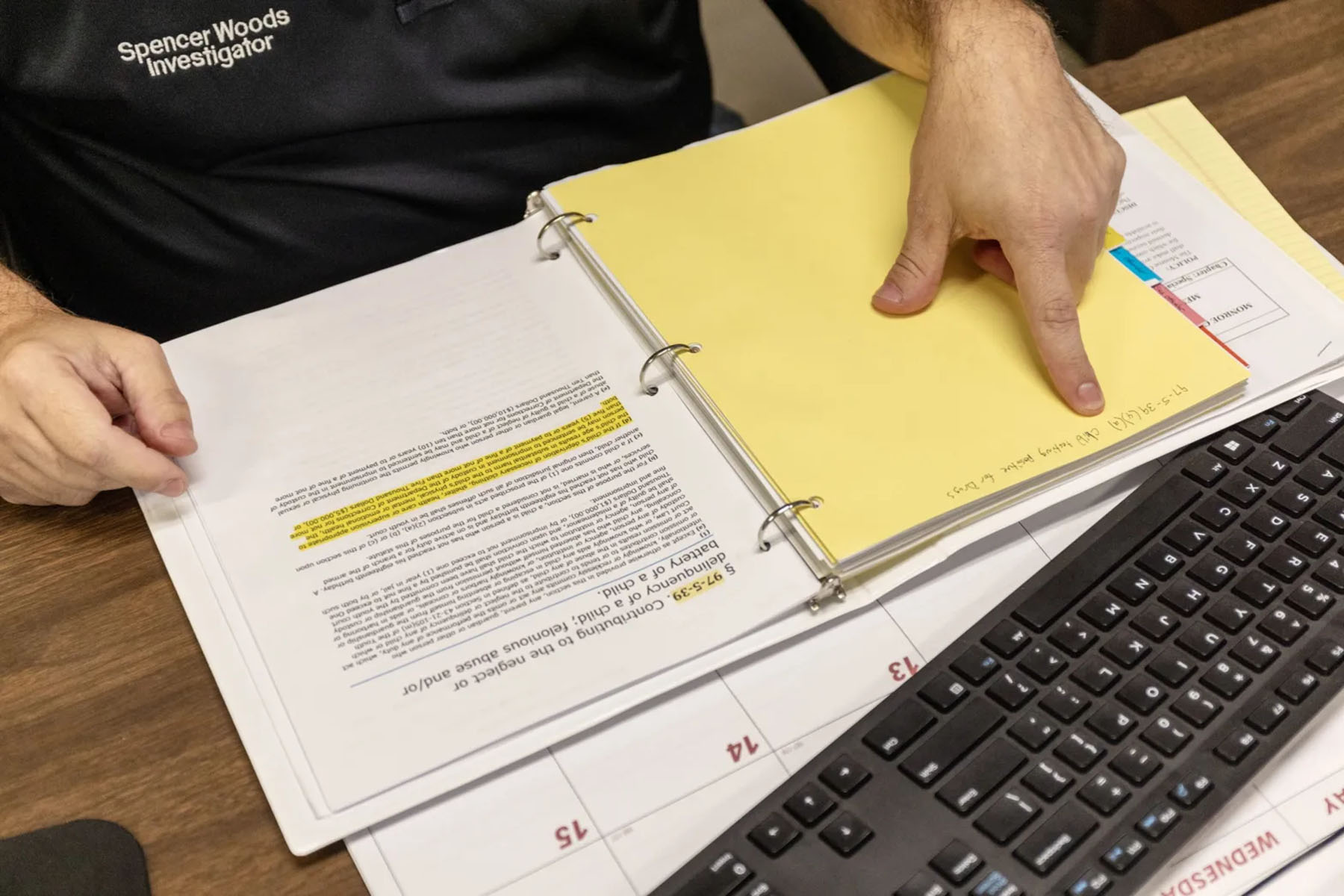 Spencer Woods points at a criminal code jotted down on a binder on his desk.