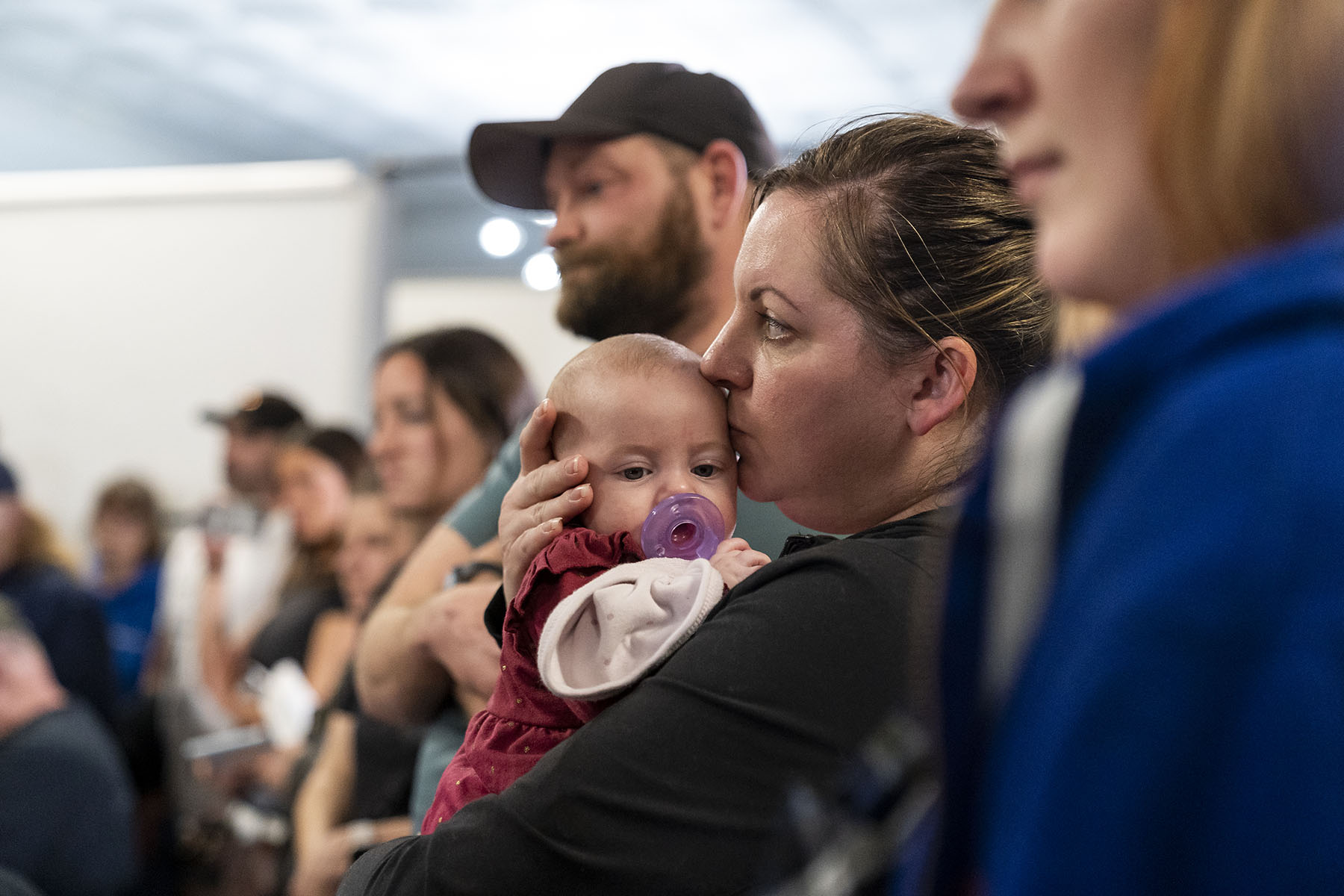 Resident Stacey Sevacko kisses her baby as she attends a town hall meeting about the environmental impact of the derailment.