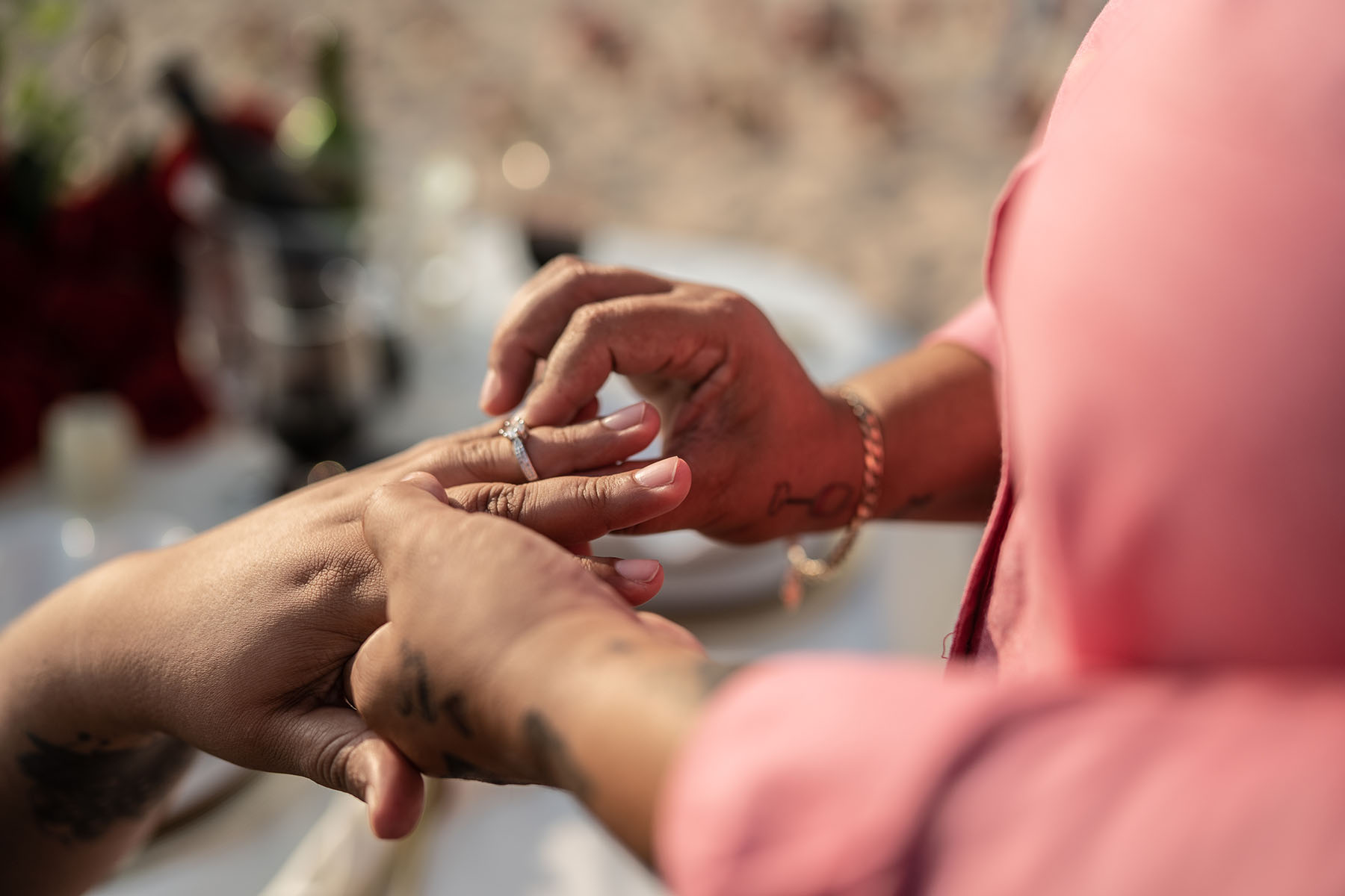 A woman puts a ring on her girlfriend after proposing to her on the beach.