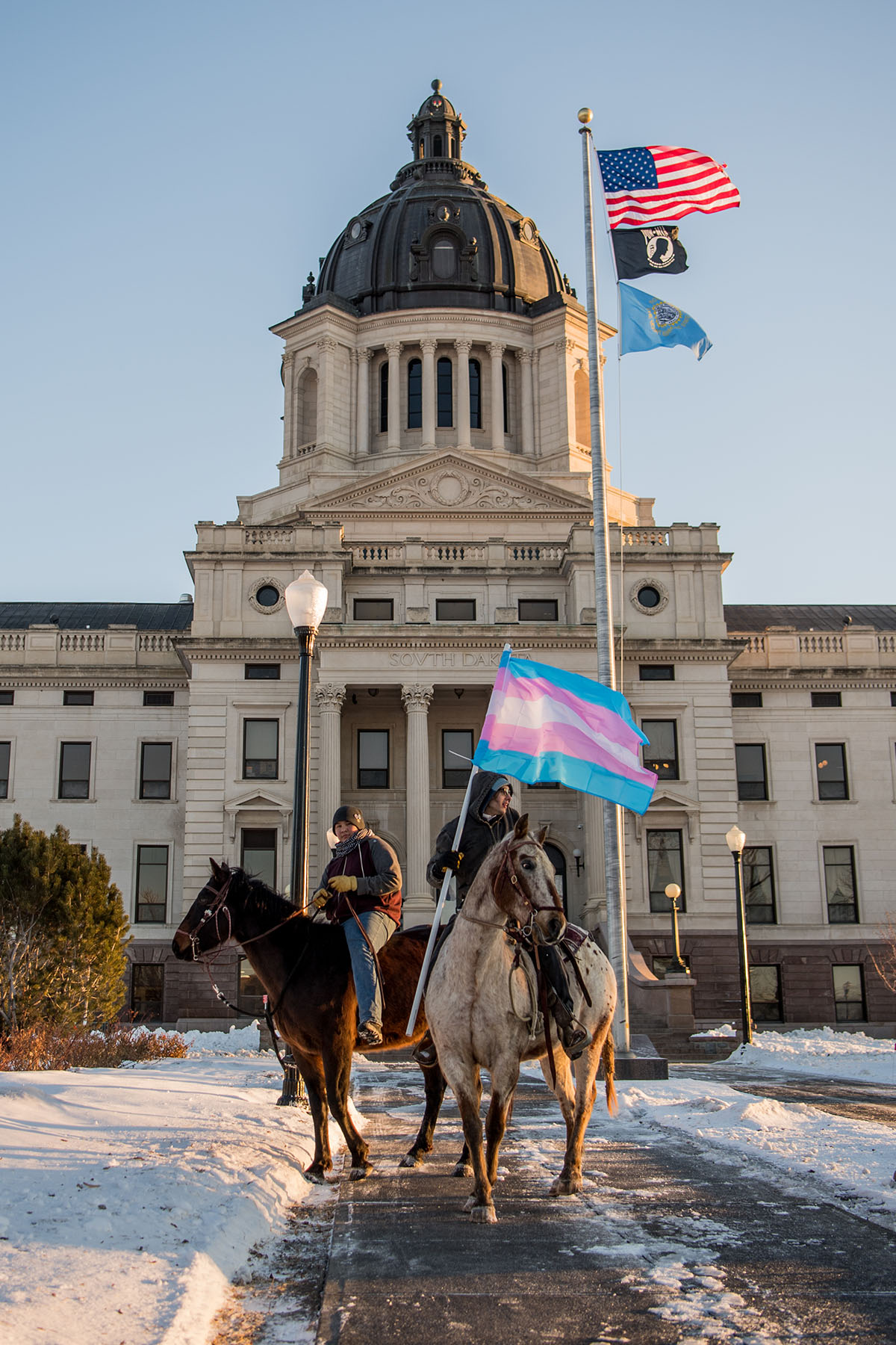 Two Native riders are seen on the South Dakota Capitol lawn on horseback.