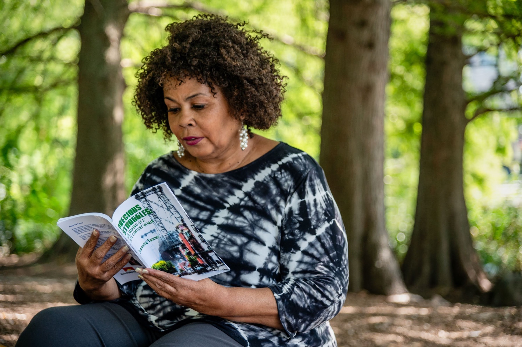 A Black woman reads a book in New York's Central Park.