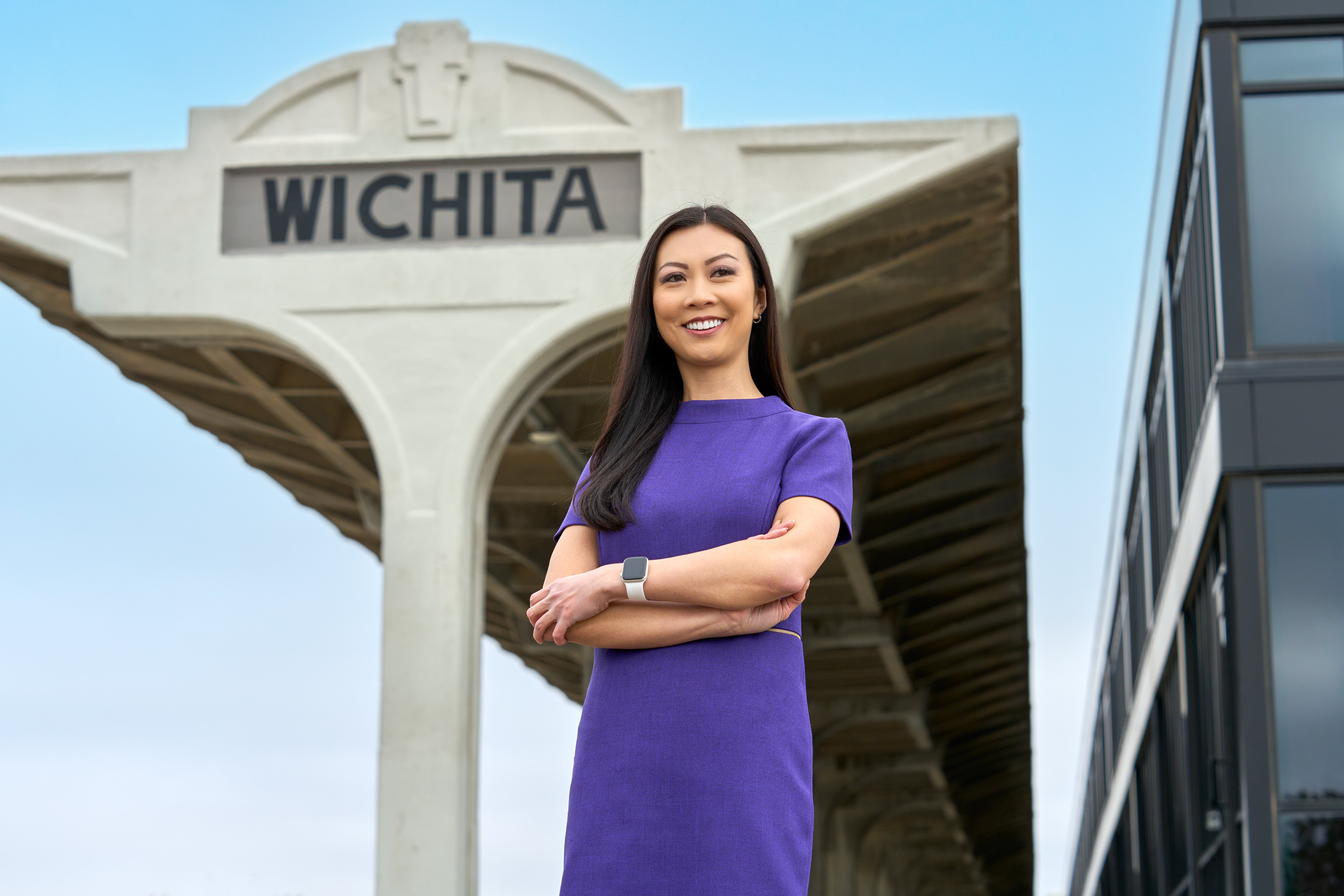 Lily Wu smiles as she poses in front of a sign for Wichita, Kansas.