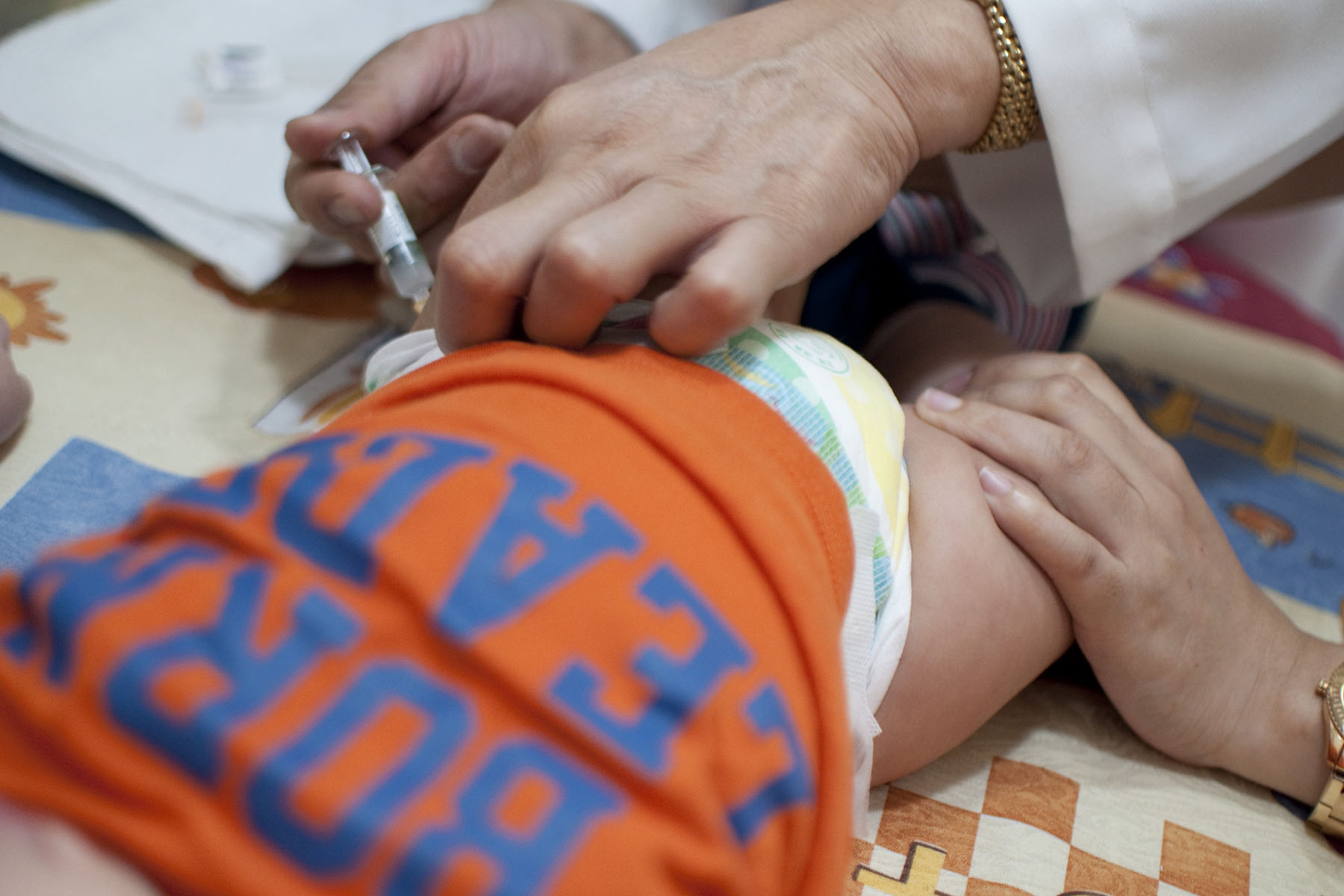 A baby receives a shot into his thigh muscle.