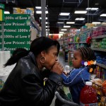 A grandmother gives their grandchild a kiss on the hand as they grocery shop together.