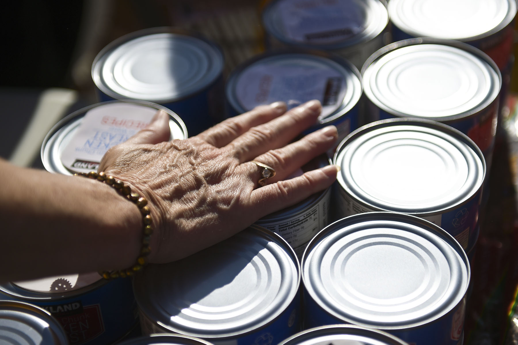 A woman's hand is seen resting on canned goods.