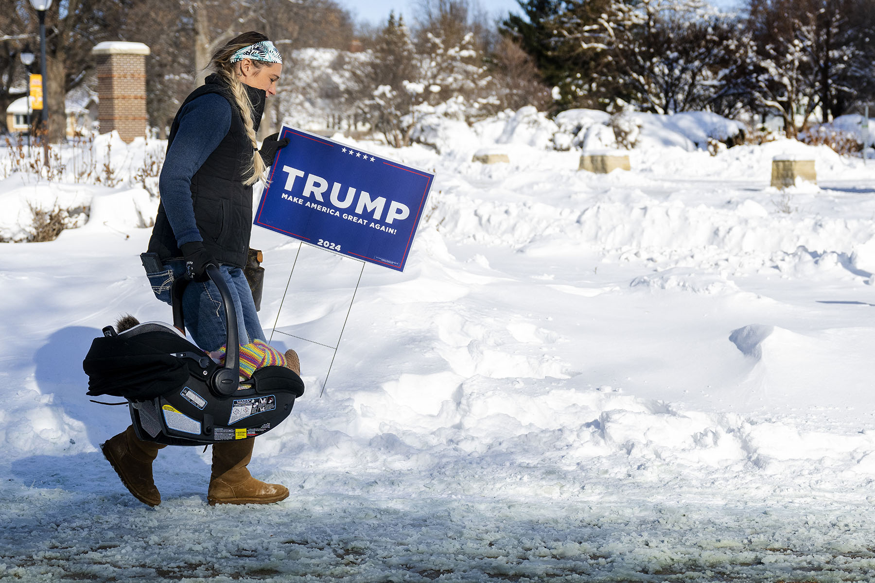 A Donald Trump supporter carries her baby and a Trump placard as she braves the below zero temperatures to attend a rally in Indianola, Iowa.