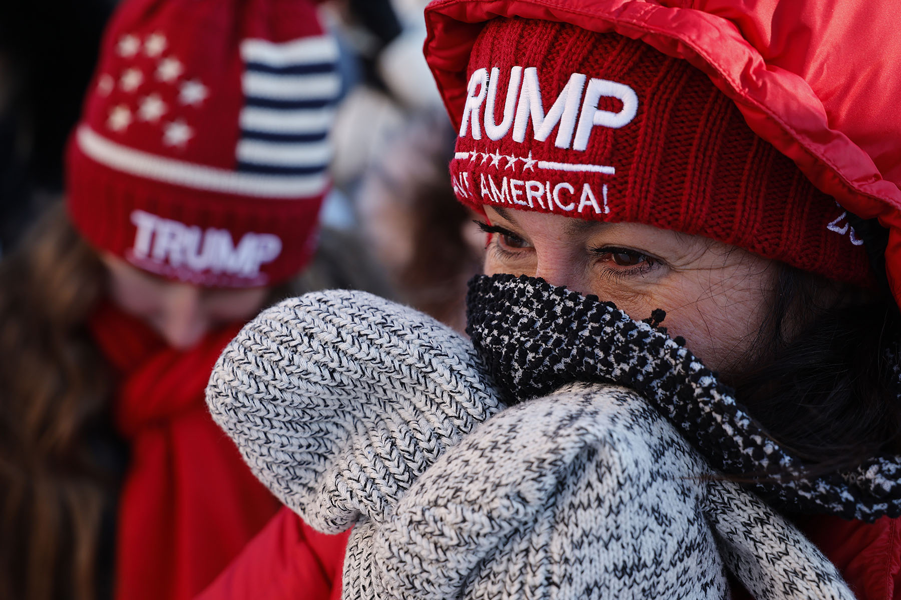 Supporters of former President Donald Trump bundle up against the cold while waiting outside the Rochester Opera House ahead of a campaign rally.