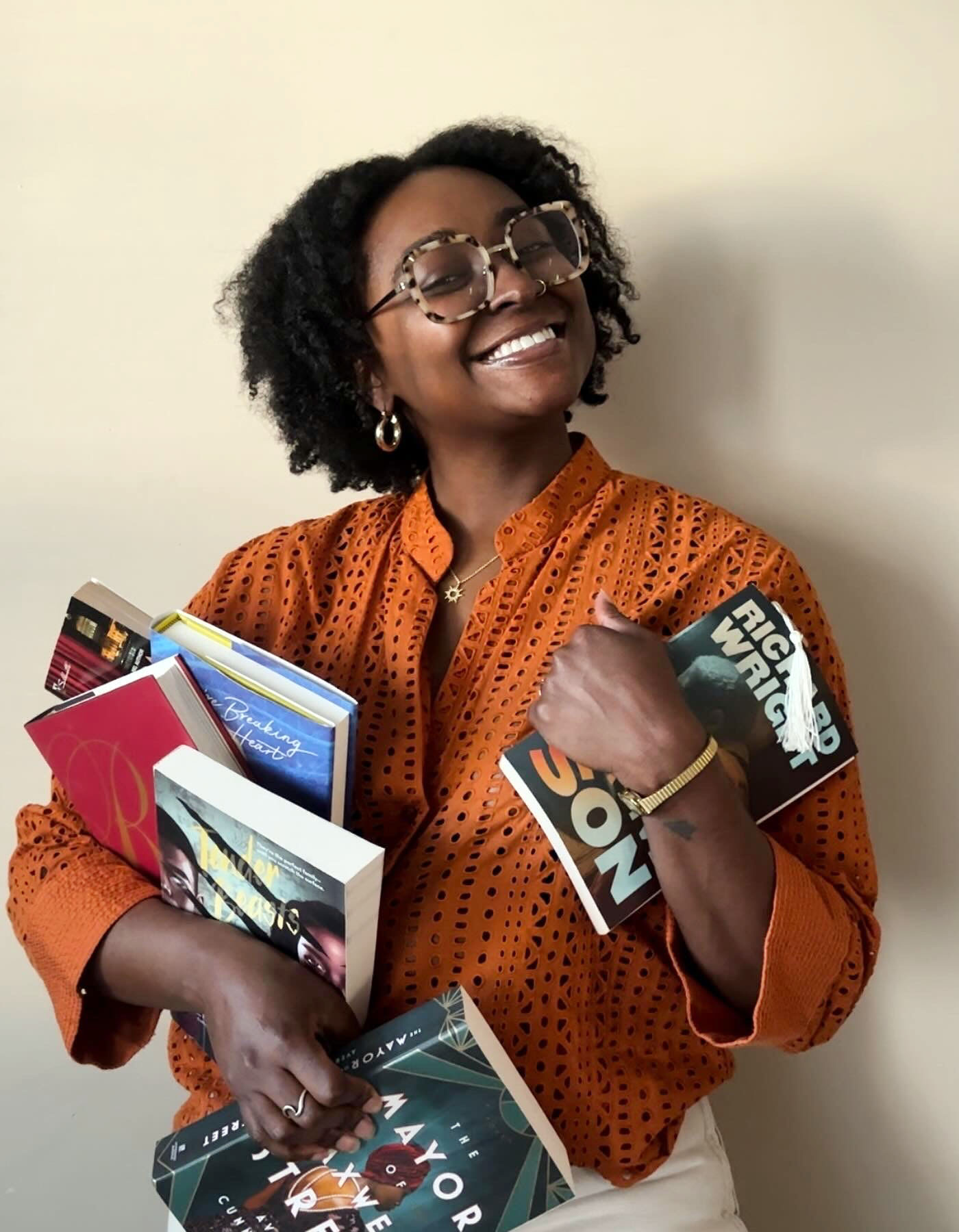 Portrait of Dawnshaeé Reid holding lots of different books while smiling.