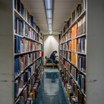 A student is seen reading between stacks of books at the Rice University Library.