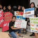 A group of young folks hold signs that read 