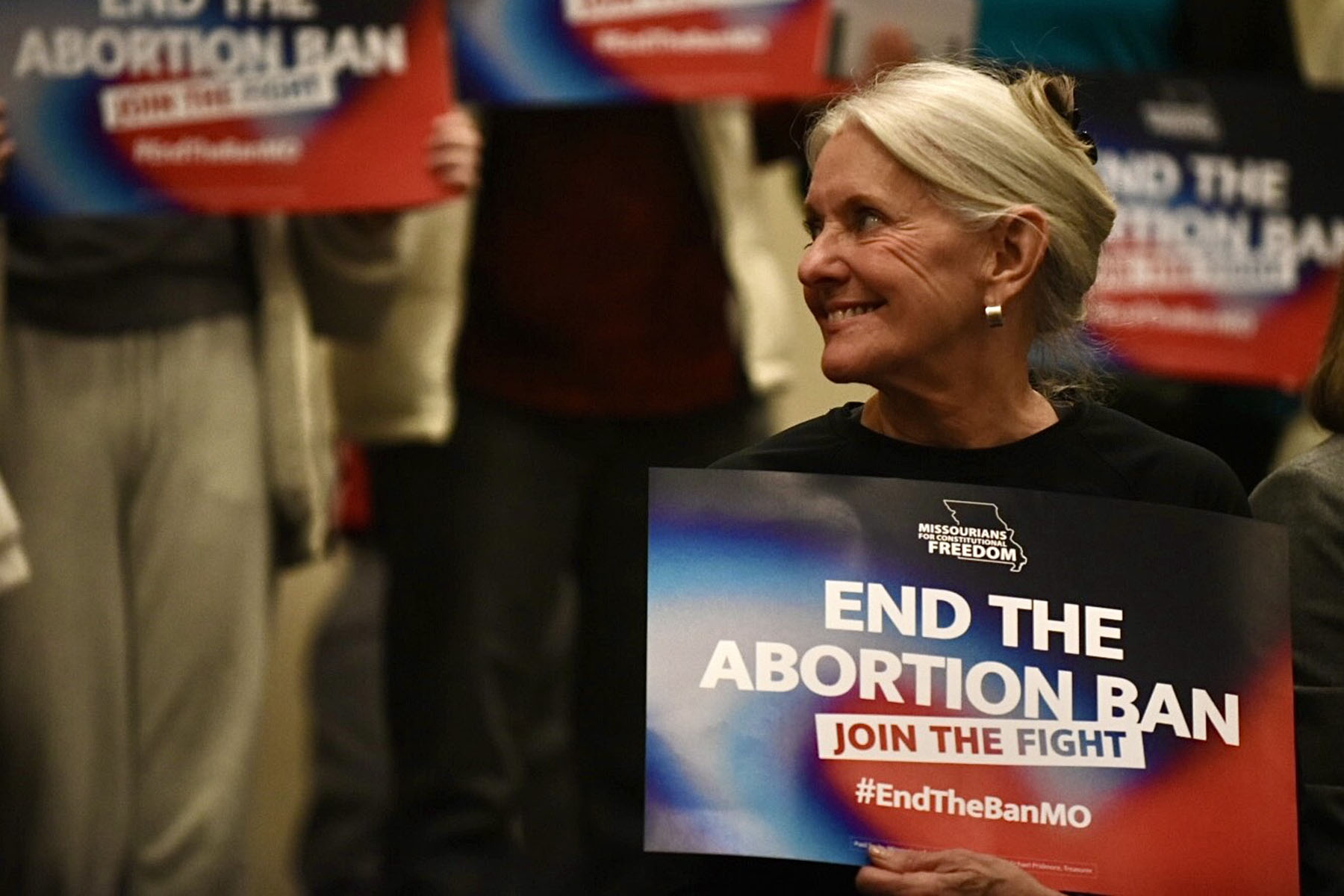 A volunteer with Missourians for Constitutional Freedom holds a sign that reads "End The Abortion Ban: Join The Fight"