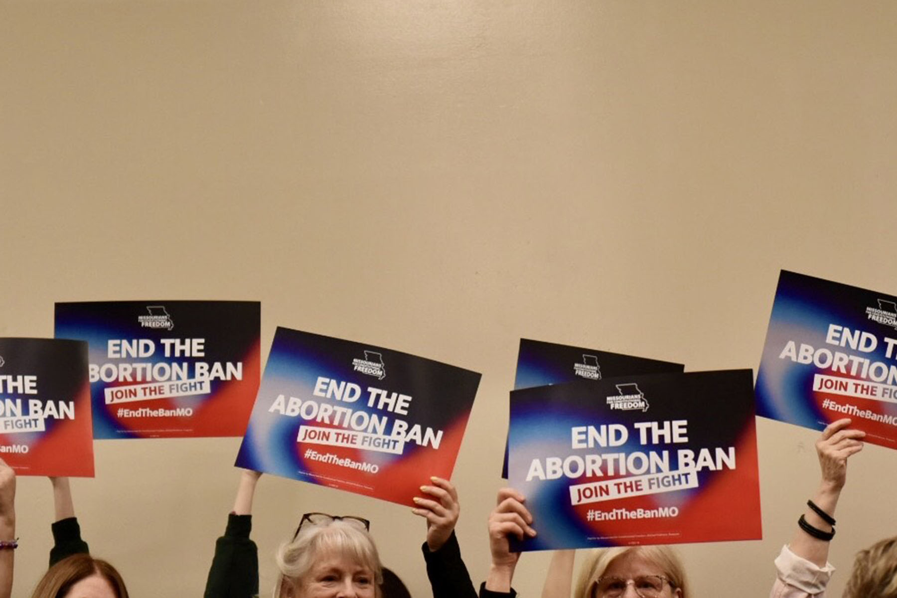 Supporters of a campaign hoping to amend the state constitution to roll back Missouri’s abortion ban lift signs that read "End The Abortion Ban: Join The Fight"
