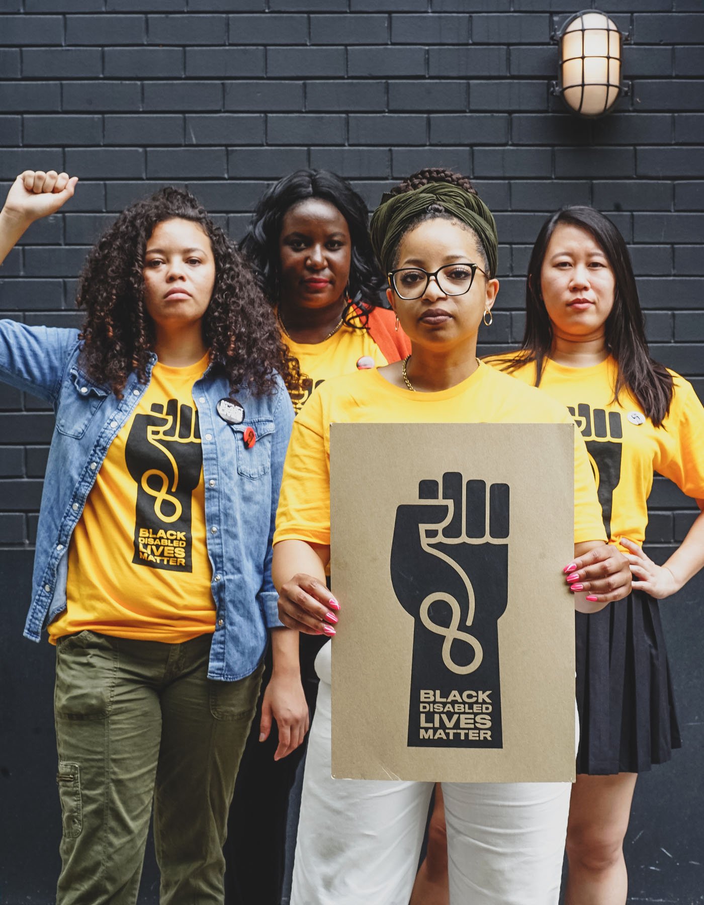 Women wearing shirts with the Black Disabled Lives Matter logo pose together.