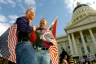 With an American flag draped over their shoulders and a rainbow flag in hand, Jim Gatteau and Mike Holland take part in a rally for gay marriage rights in front of the California state capitol.