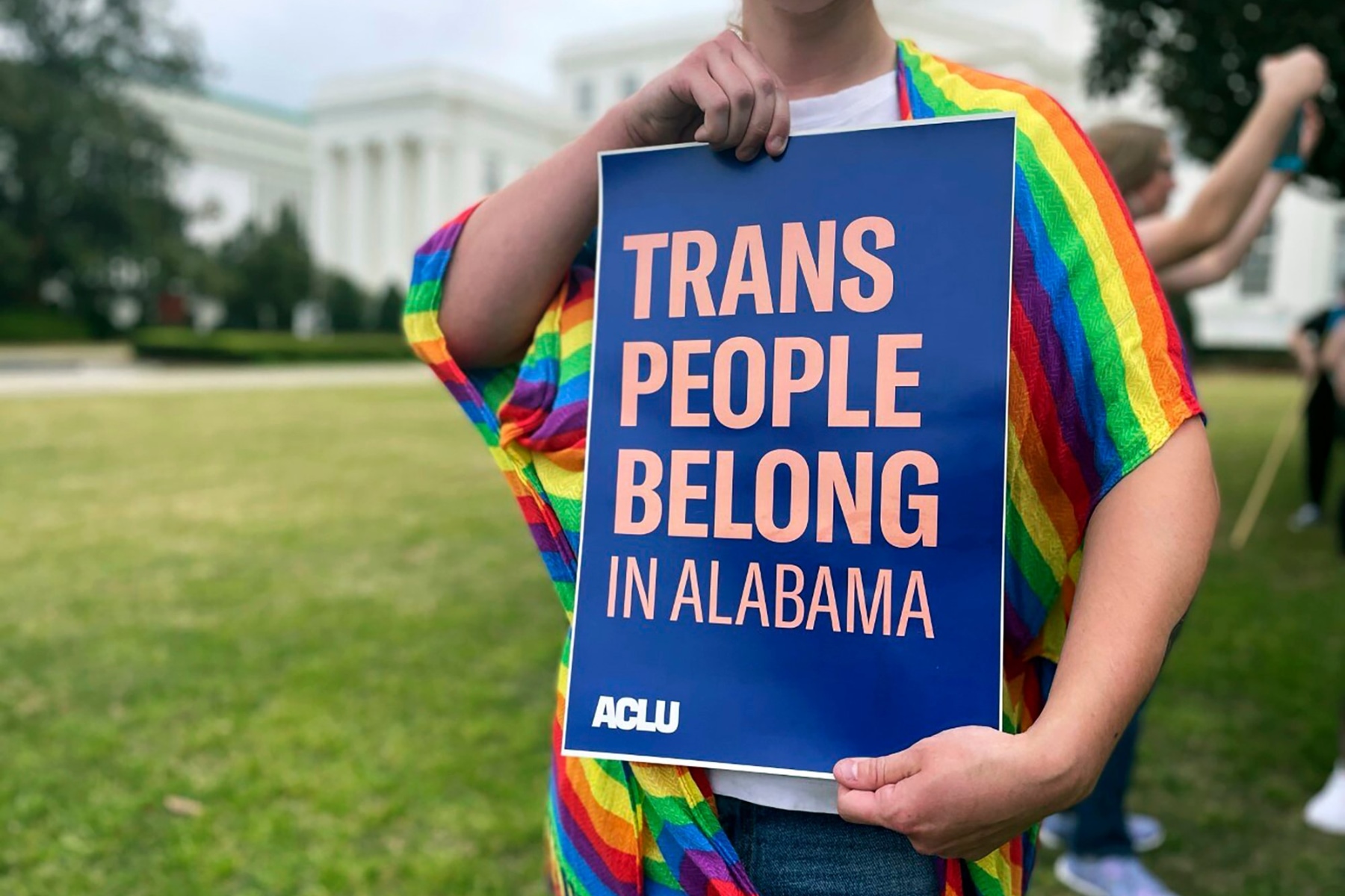 A person holds up a sign reading, "Trans People Belong in Alabama," during a rally.