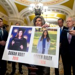 Sen. Joni Ernst holds a poster with photos of murder victims Sarah Root and Laken Riley as she is surrounded by press and other senators.