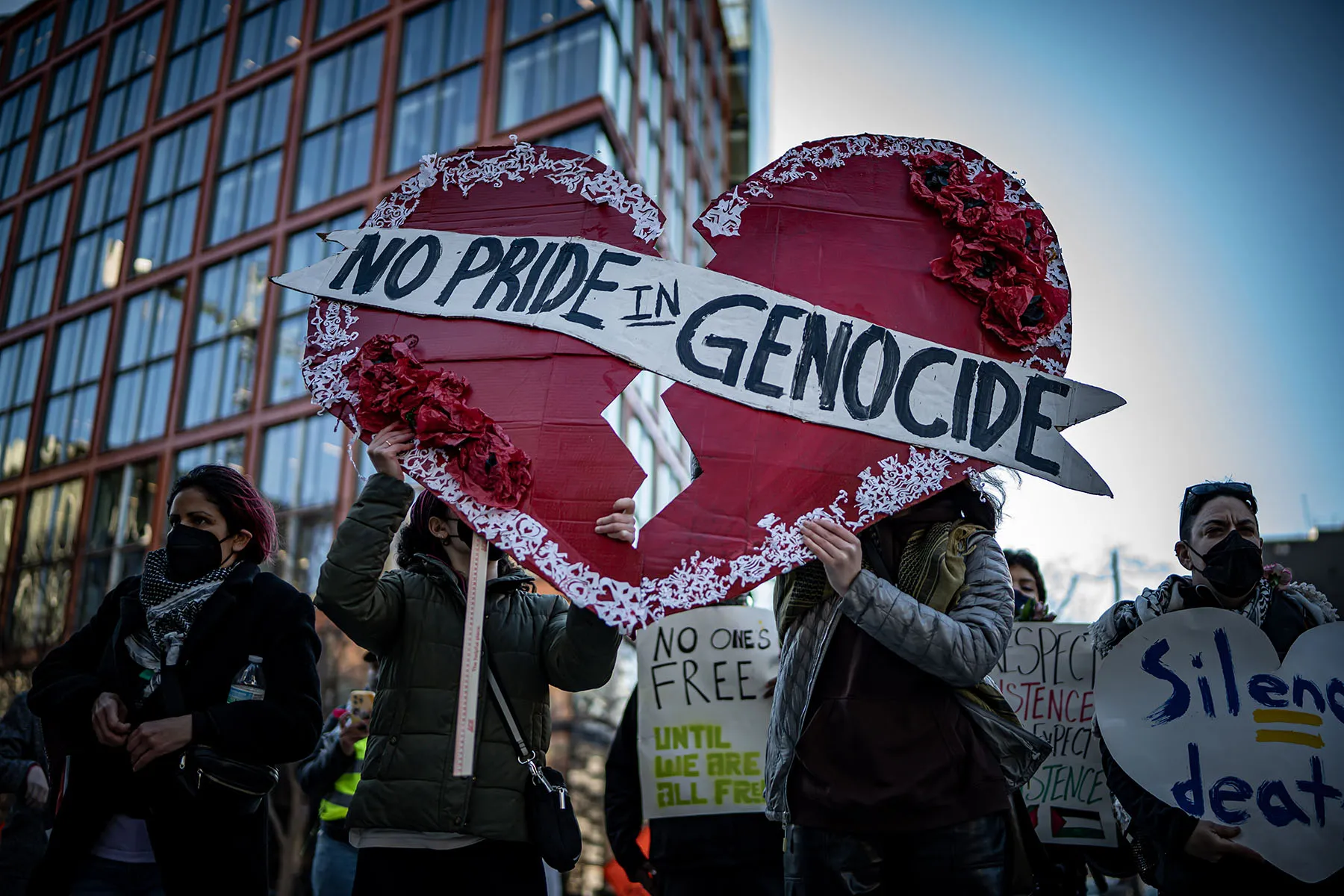 Two people hold a broken heart that reads "No Pride in Genocide" during a rally near the Human Rights Campaign headquarters.