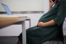 Pregnant woman sitting at a desk at work.