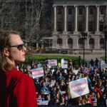 An attendee looks over a crowd of demonstrators at a rally to protest the passing of an anti-trans bill.