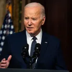 President Joe Biden speaks in front of microphones