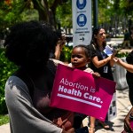 A black woman holds a child during an abortion rights protest in Florida.