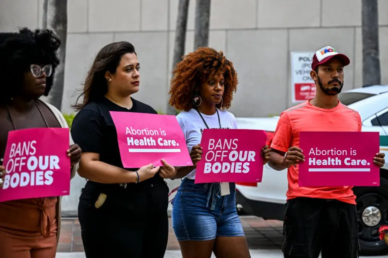 Members of Florida Planned Parenthood PAC Abortion rights activists hold signs that read "Abortion is healthcare" and "bans of our bodies" in Miami during a protest.