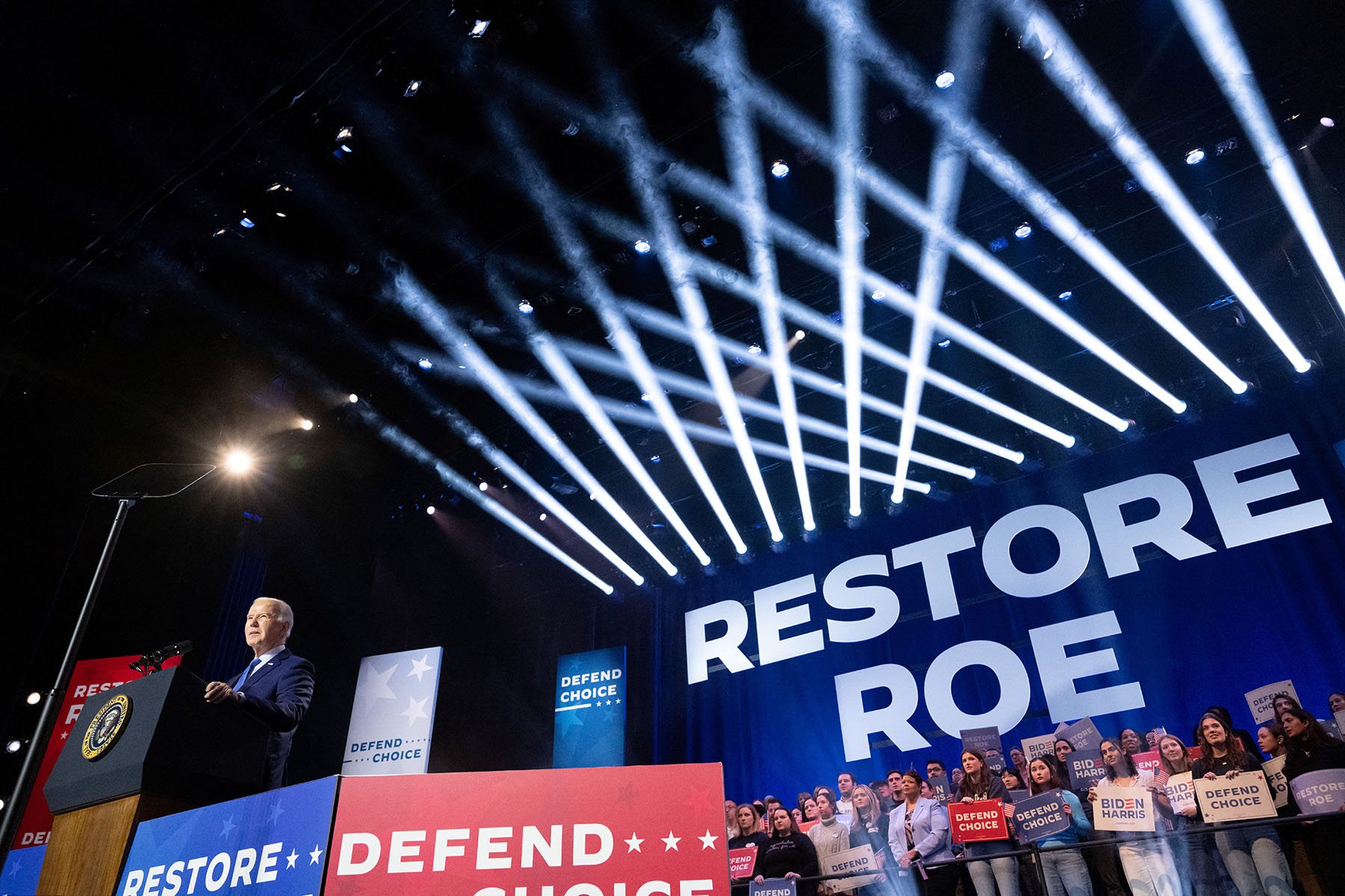 President Biden speaks during a campaign rally in Manassas, Virginia, in January 2024. Behind him, a large curtain reads "Restore Roe"