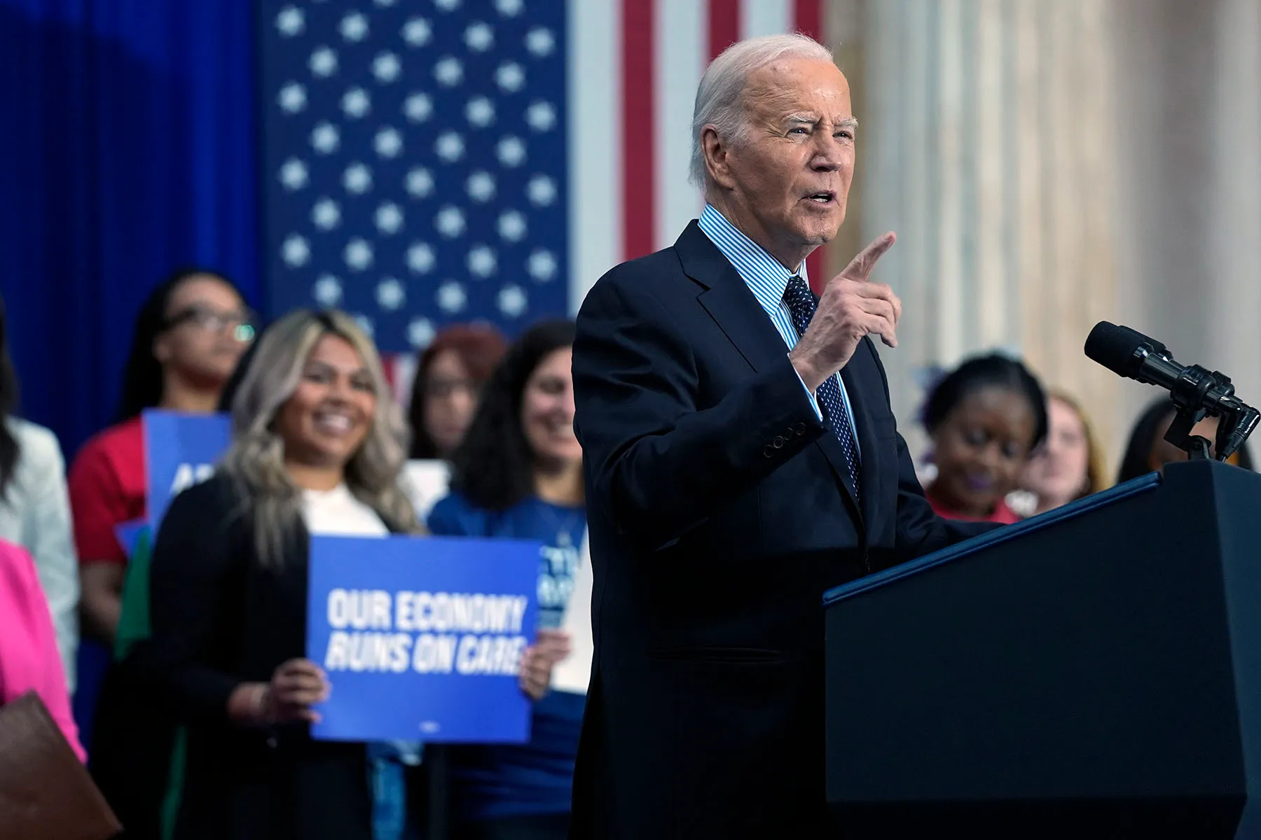 President Biden is seen at a podium delivering remarks on proposed spending on child care and other investments in the "care economy."
