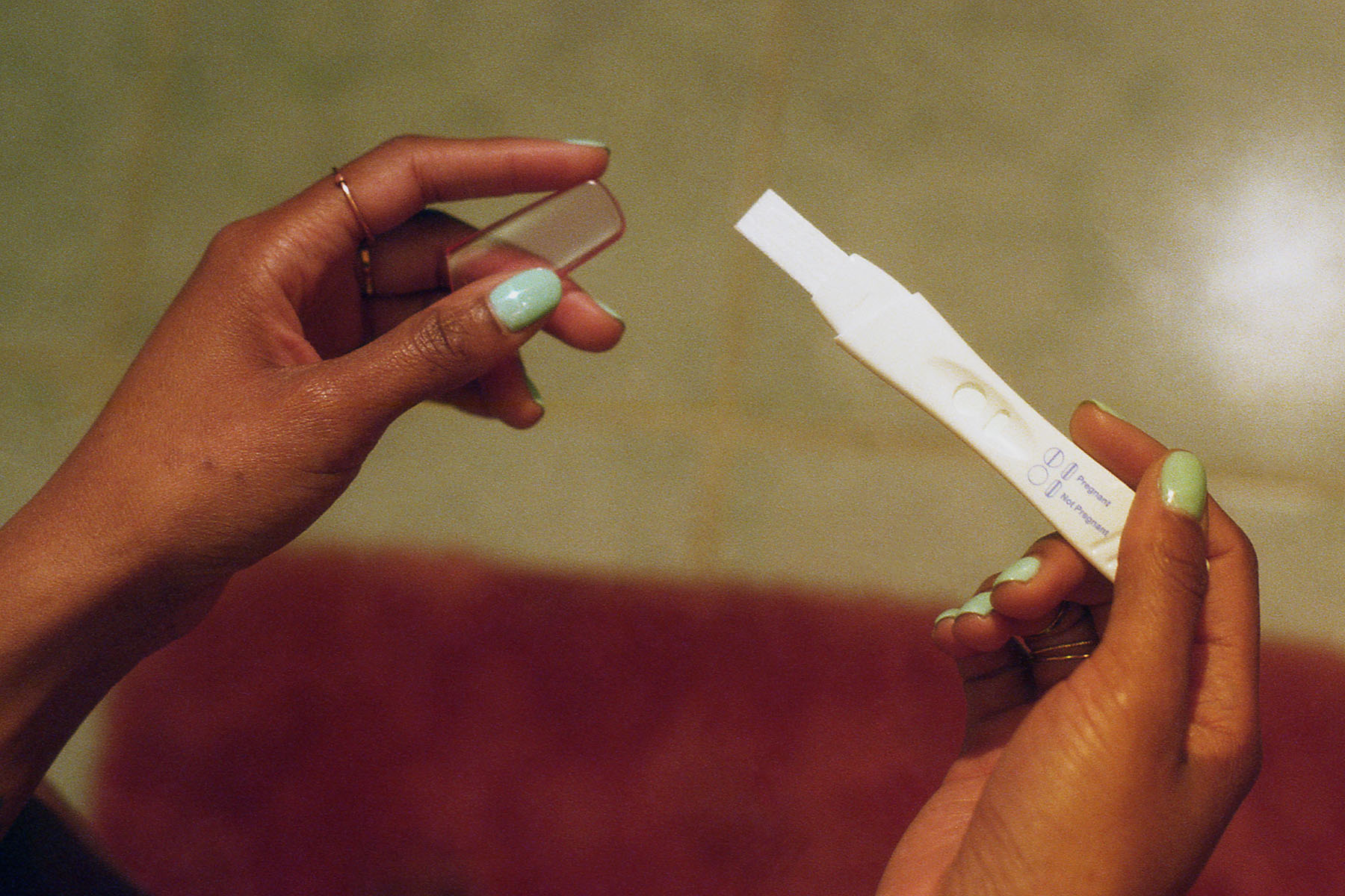 young black woman looking at pregnancy test.