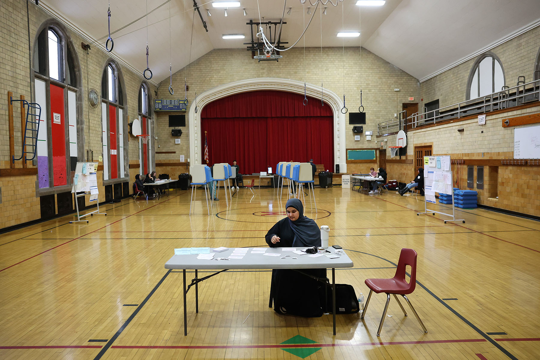 A poll worker wears a hijab as she sits at check-in table at Maples Elementary School.