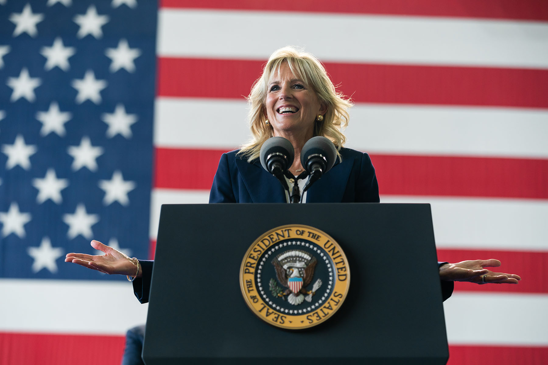 First Lady Jill Biden delivers remarks from a podium. Behind her is an American flag.